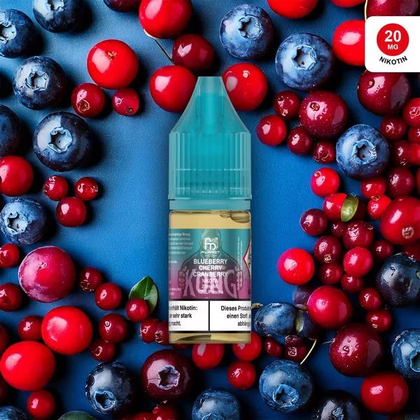 Produktbild des RandM Liquids in der Sorte Blueberry Cherry Cranberry. Eine 10ml Liquidflasche mit türkisem Verschluss steht im Zentrum, umgeben von einem Mix aus frischen Blaubeeren, Kirschen und Cranberries auf einem dunkelblauen Hintergrund. Das Etikett zeigt das charakteristische FUMOT-Affen-Logo auf lila-blauem Grund. Oben rechts befindet sich ein roter Button mit dem Hinweis „20 MG NIKOTIN“. Ein deutscher Gesundheitshinweis ist deutlich am unteren Rand der Flasche platziert.