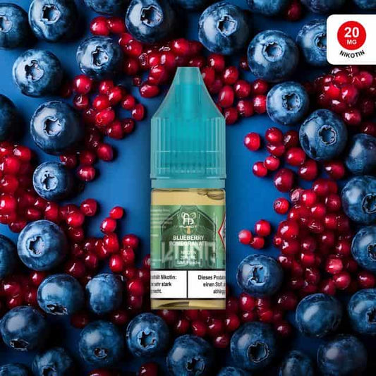 Produktbild des RandM Liquids in der Sorte Blueberry Pomegranate. Eine 10ml Liquidflasche mit türkisem Verschluss steht im Zentrum, umgeben von frischen Blaubeeren und leuchtend roten Granatapfelkernen auf einem dunkelblauen Hintergrund. Das grüne Etikett zeigt das charakteristische „King Kong“ Affen-Logo von FUMOT. Oben rechts befindet sich ein roter Button mit dem Hinweis „20 MG NIKOTIN“. Ein deutscher Gesundheitshinweis ist deutlich am unteren Rand der Flasche platziert.