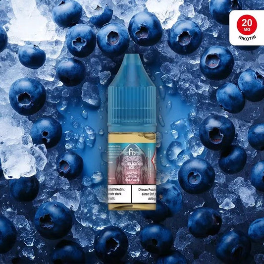Produktbild des RandM Liquids in der Sorte Bluelicious Ice. Eine 10ml Liquidflasche mit blauem Verschluss steht im Zentrum, umgeben von frischen Blaubeeren und Crushed Ice auf einem kühlen blauen Hintergrund. Das Etikett zeigt das charakteristische FUMOT-Affen-Logo auf bläulichem Grund. Oben rechts befindet sich ein roter Button mit dem Hinweis „20 MG NIKOTIN“. Ein deutscher Gesundheitshinweis ist deutlich am unteren Rand der Flasche platziert.