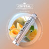 Produktabbildung der Crystal Bar Honey Melon Einweg E-Zigarette vor einem Hintergrund mit geschnittenen Honigmelonen. Das Gerät ist silberfarben-transparent mit Kristalloptik. Im Hintergrund sind frische Melonenhälften sowie das Logo und Produktinformationen wie '2ml', '600+ Puffs' und 'Mesh Coil' zu sehen.